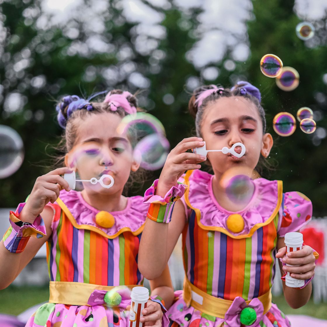 Dos niñas con vestidos de colores haciendo burbujas de jabón