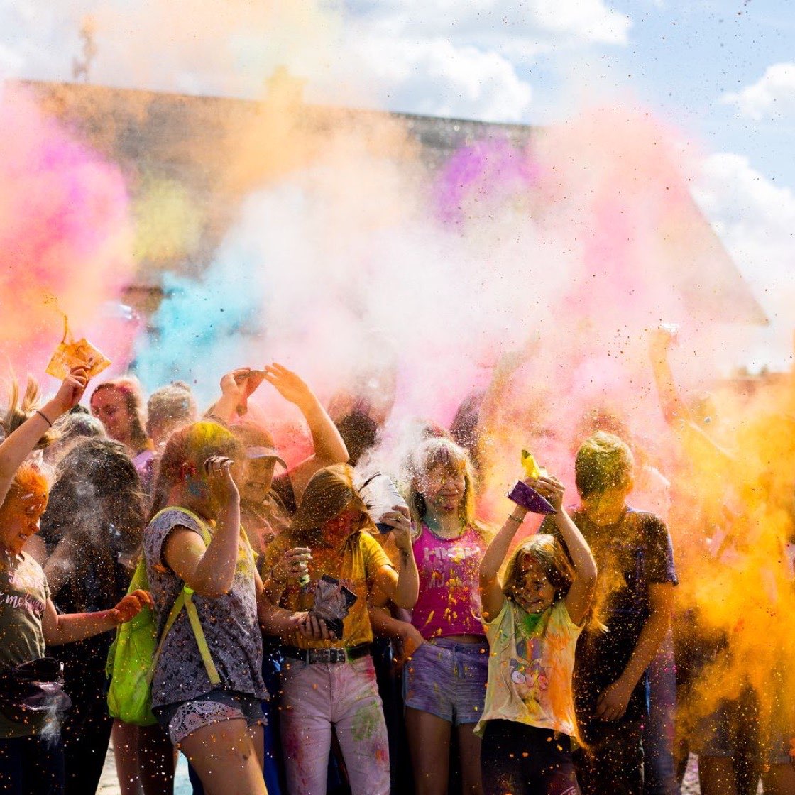Público lanzando polvos de colores en un festival al aire libre