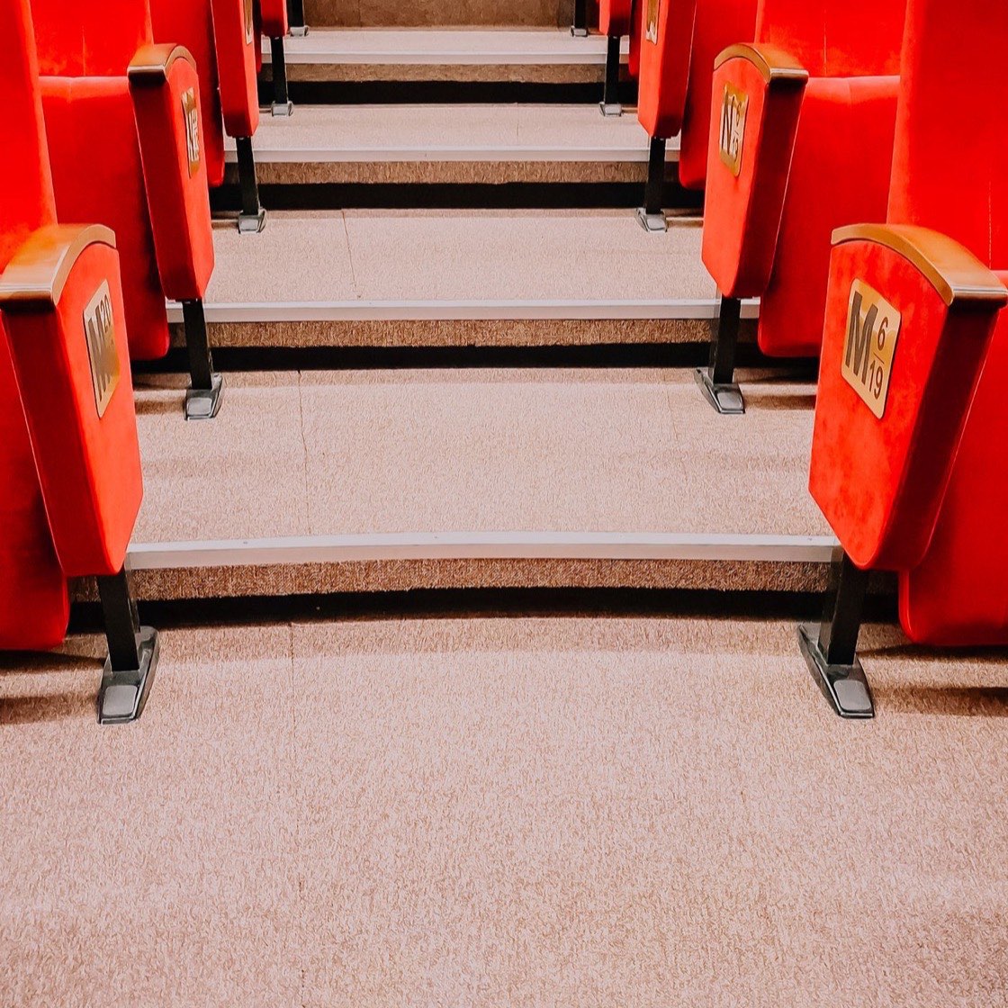 Butacas rojas de un teatro con su fila y número