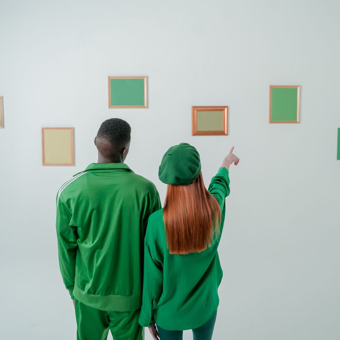 Pareja vestida de verde mirando cuadros en una exposición