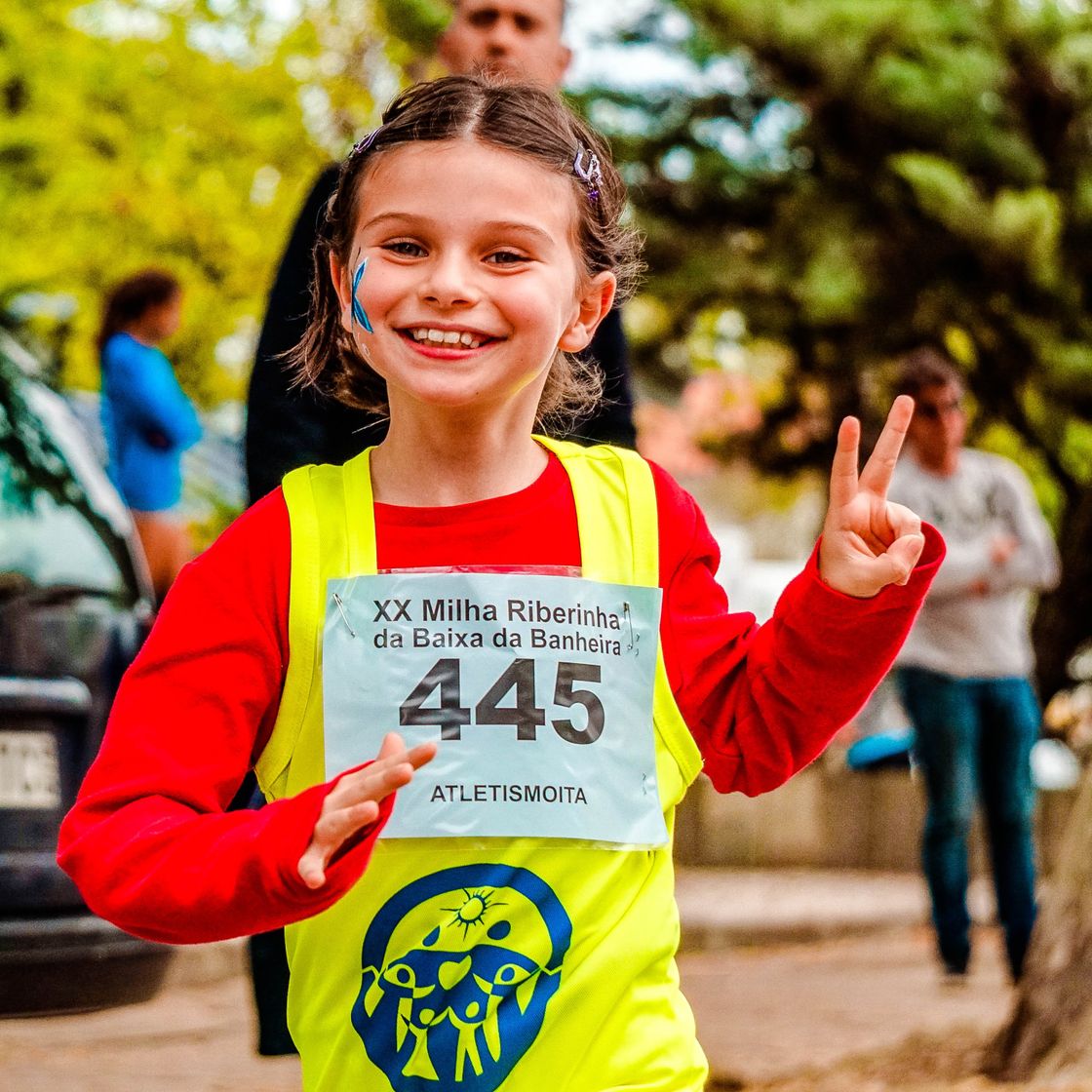 Niña con su número de corredora sonriendo en una carrera
