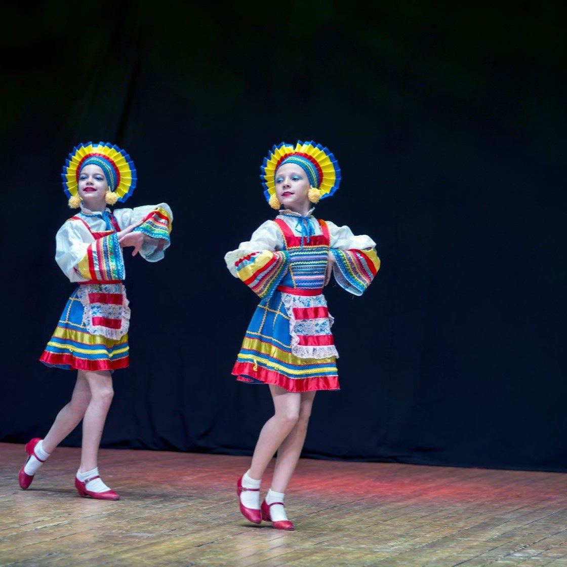 Niñas bailando en un escenario con trajes de colores