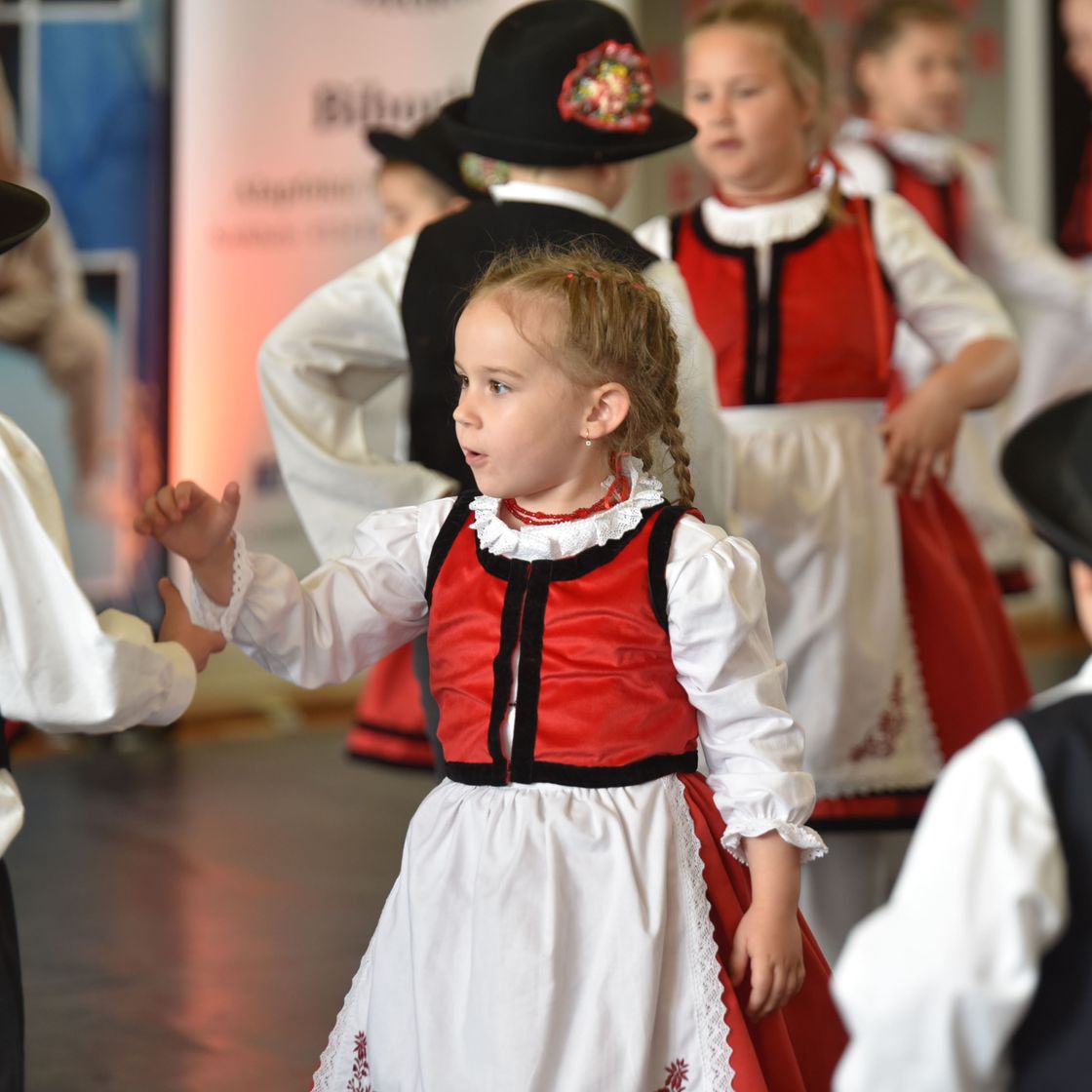 Niña con traje típico bailando con su grupo en un festival escolar