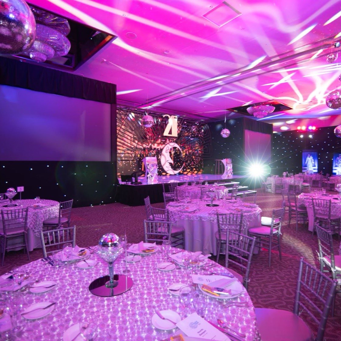 Salón de eventos con iluminación rosa y mesas para cena