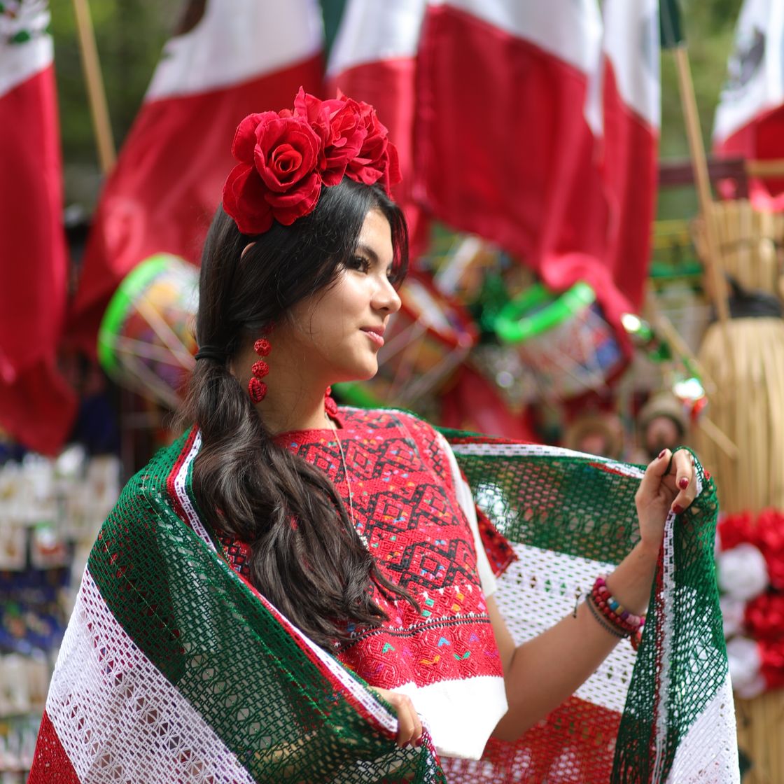 Mujer con vestido mexicano, rebozo tricolor y flores rojas