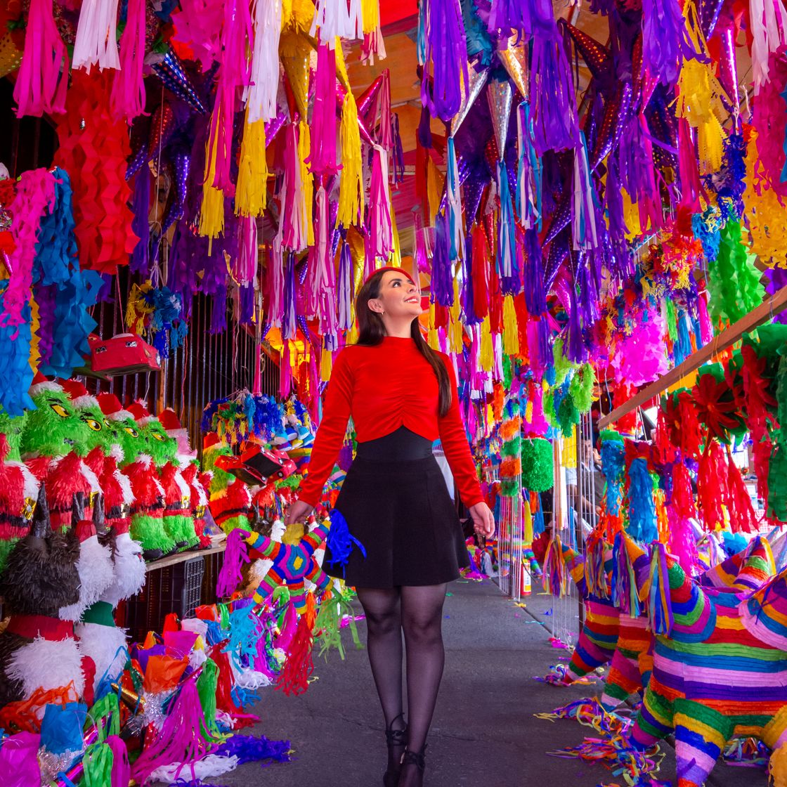 Mujer caminando entre piñatas de colores
