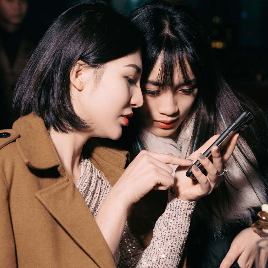 Dos amigas revisando juntas su celular en la noche del evento